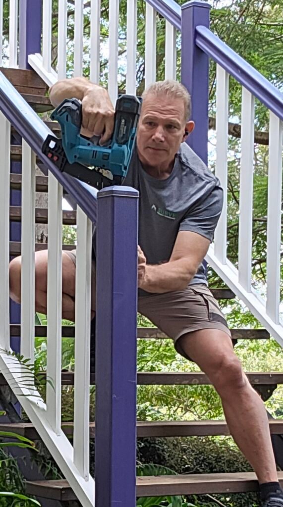 Handyman drilling a fixing on a timber stair balustrade