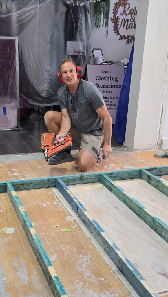 Handyman building a timber floor frame in a retail shop fit-out
