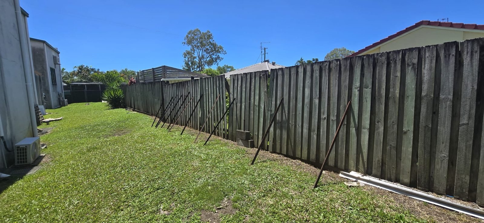 Before: leaning timber fence propped up with steel stakes