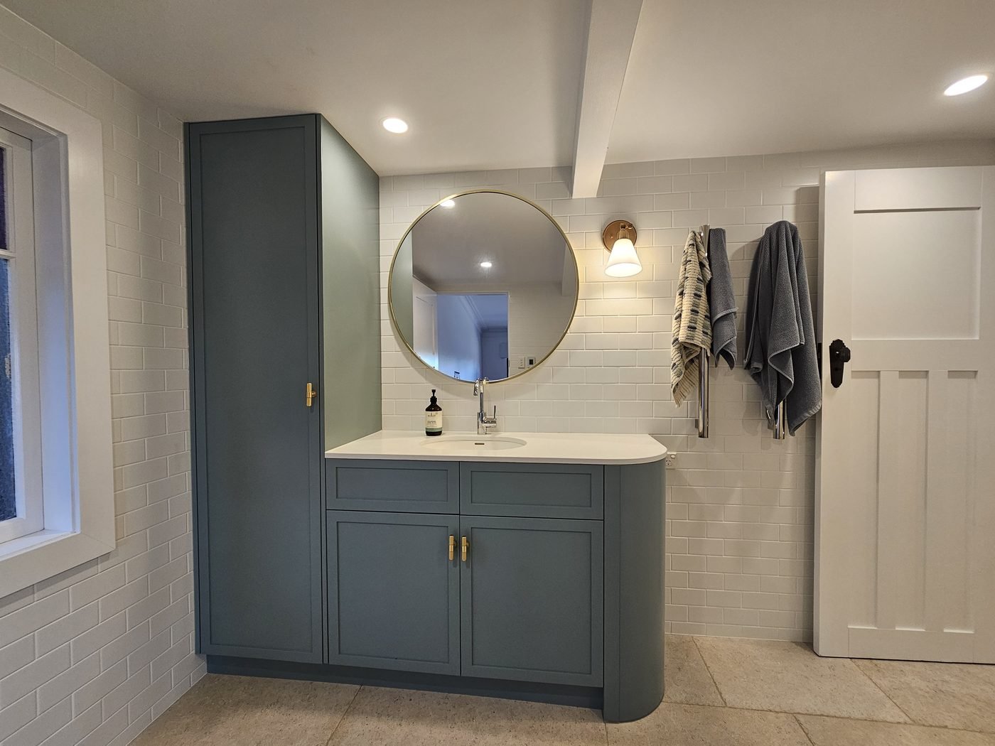 After: renovated bathroom with custom vanity, tall cabinet and round mirror by SURVE