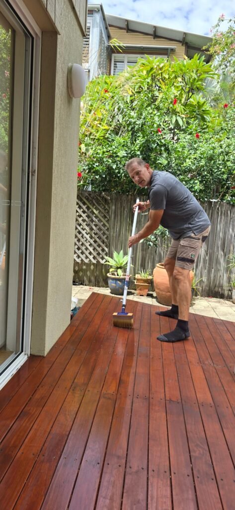 Handyman oiling a new timber deck