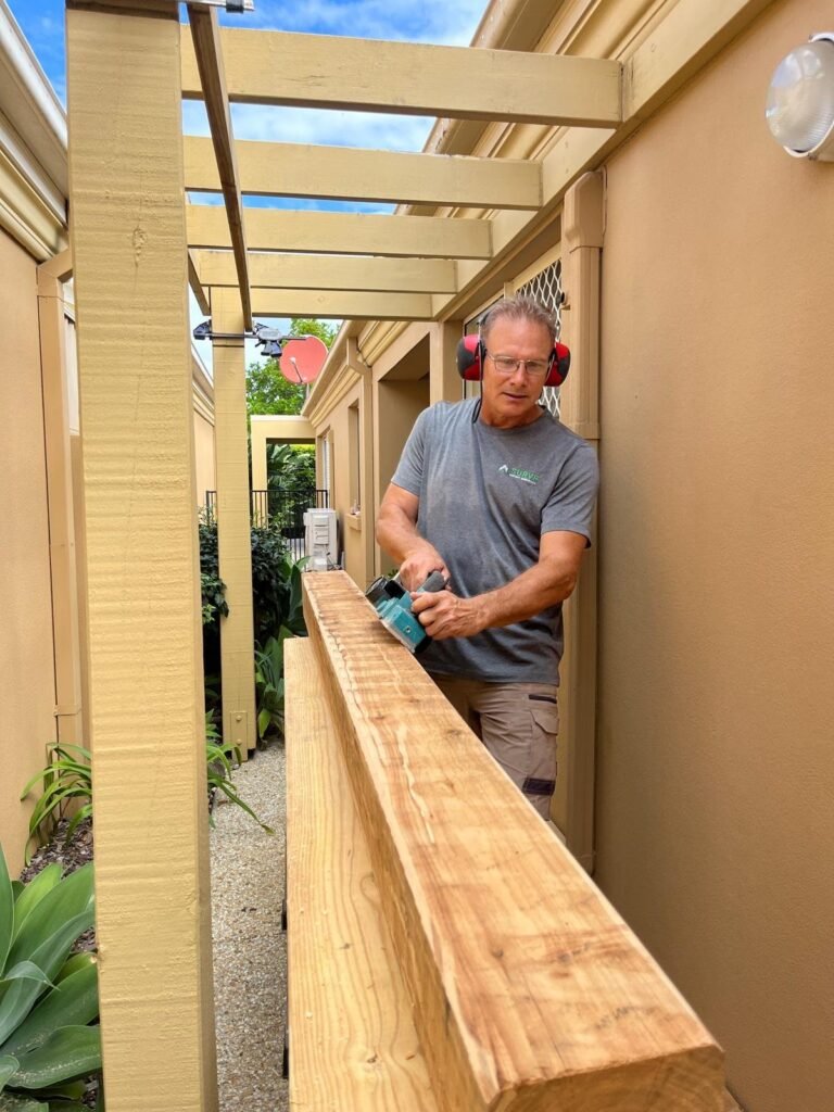 Handyman planing a timber beam for a pergola