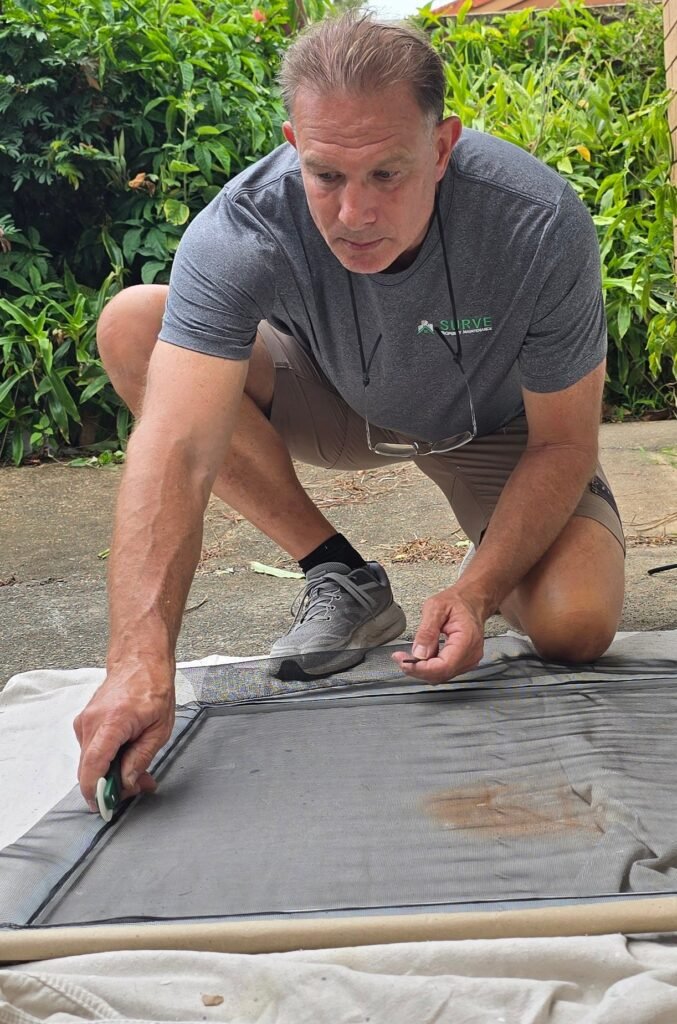Handyman replacing flyscreen mesh on a frame